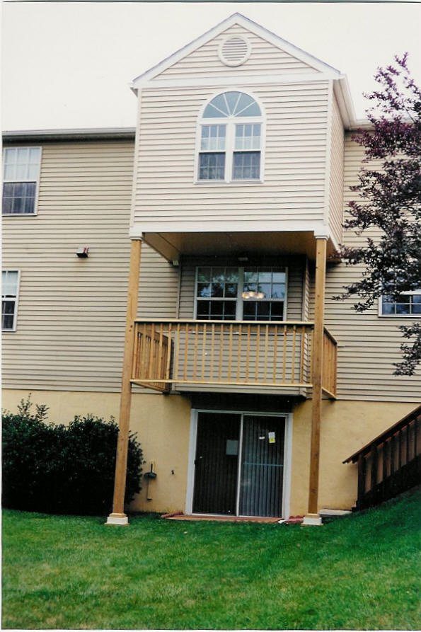 Two-story balcony with wooden railings on a beige house.