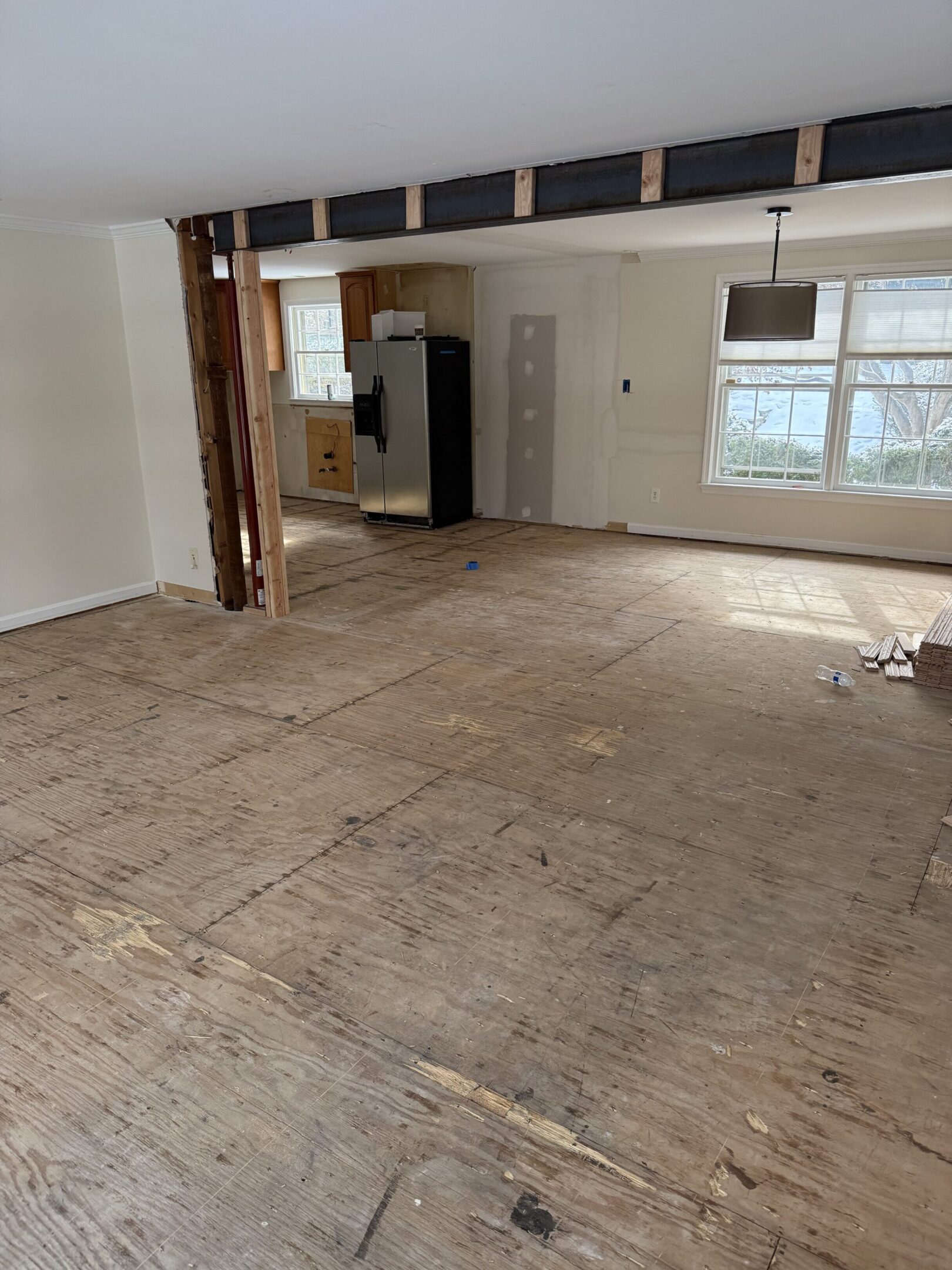 Empty room with worn wooden floor and exposed beams.