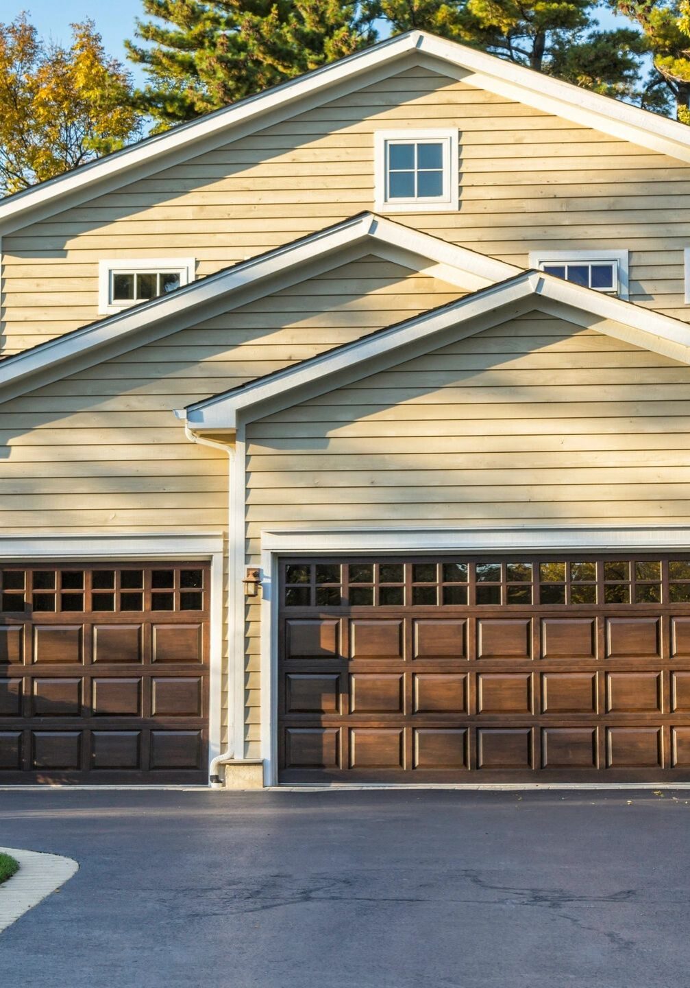 Modern suburban house with a three-car garage and wooden doors.